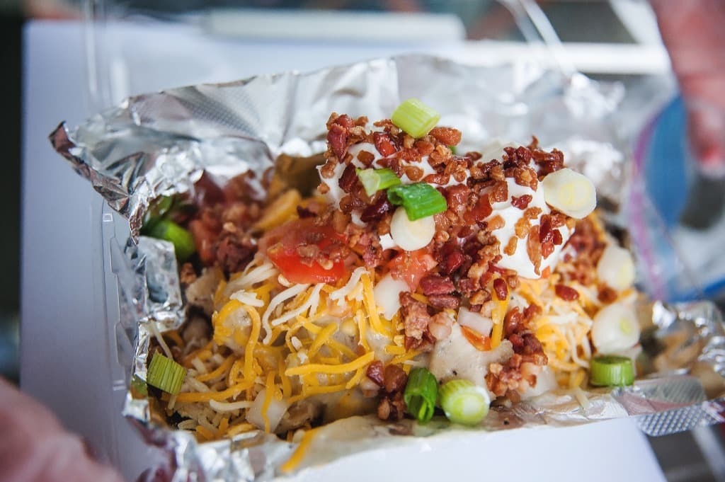 A loaded stuffed potato topped with cheese, bacon, and green onions