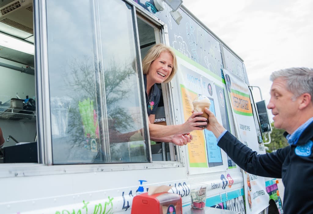 An owner handing a drink through the truck service window